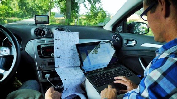 Meeno Schrader mit Laptop und Wetterkarten auf dem Beifahrersitz © NDR Foto: Juliane Thomas