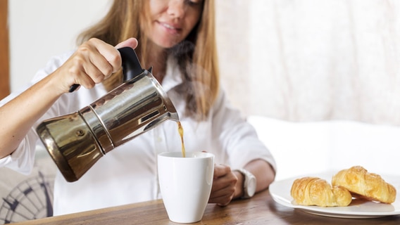 Eine Frau gießt Kaffee in einen Becher © imago 