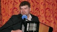 Jan Graf singt zur Quetsche selbst komponierte Lieder in Molfsee bei der Veranstaltung "Ünner't Strohdack". © NDR Foto: Gyde Jensen
