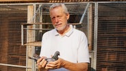 Matthias Warzecha aus Oering hält eine Taube in den Händen. © NDR Foto: Jelto Ringena