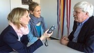 Zwei Frauen interviewen Werner Junge und zeichnen die Unterhaltung mit einem Tonaufnahmegerät auf. © NDR Foto: Lornz Lorenzen