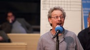 Achim Kussmann spricht beim Platt Poetry Slam in ein NDR Mikrofon. © NDR Foto: Lornz Lorenzen