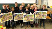 Schüler einer dritten Klasse präsentieren ein Plakat zu einem plattdeutschen Lehrbuch. © NDR Foto: Werner Junge