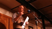 Jan Ladiges steht auf der Bühne vor einem Mikrofon. © NDR Foto: Lornz Lorenzen