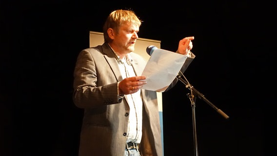 Poetry Slammer Jan Graf steht beim Poetry Slam op Platt auf einer Bühne in der Winkelscheune in Molfsee. © NDR Foto: Lornz Lorenzen