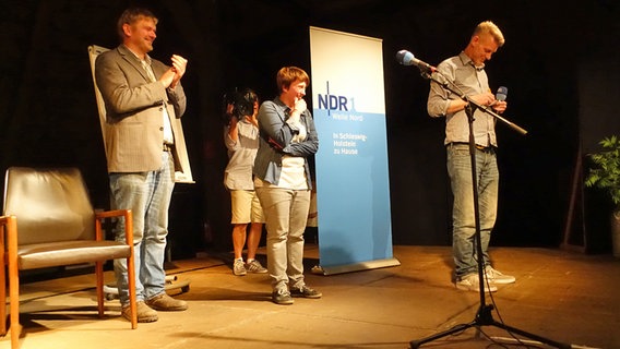 Jan Graf, Annika Blanke und Björn Högsdal stehen beim Poetry Slam op Platt auf der Bühne in der Winkelscheune in Molfsee. © NDR Foto: Lornz Lorenzen