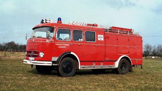 Abgebildet ist ein rotes, altes Löschfahrzeug der freiwilligen Feuerwehr Janneby aus dem Kreis Schleswig-Flensburg, das auf einer grünen Wiese steht. © Freiwillige Feuerwehr Janneby Foto: Sönke Mauderer