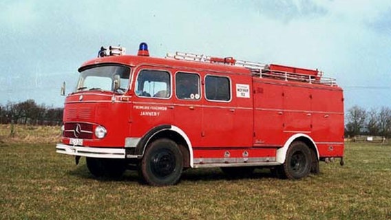 Abgebildet ist ein rotes, altes Löschfahrzeug der freiwilligen Feuerwehr Janneby aus dem Kreis Schleswig-Flensburg, das auf einer grünen Wiese steht. © Freiwillige Feuerwehr Janneby Foto: Sönke Mauderer