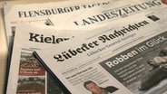 Verschiedene Schleswig-Holsteinische Tageszeitungen liegen aufeinander gestapelt auf einem Tisch. © NDR Foto: Johanna Jannsen