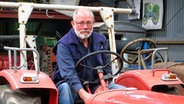 Günther Jürgensen sitzt auf einem roten Trecker und schaut in die Kamera. © NDR Foto: Peer-Axel Kroeske