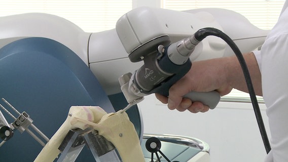 Ein Arzt bedient einen Roboter für Operationen am Knie. © NDR 