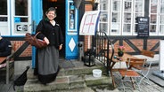 Die Stadtangestellte Rita Ihrig steht verkleidet als Stutentrine vor einem Lokal. © NDR Foto: Ines Barber