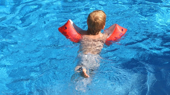 Ein Kind schwimmt mit Schwimmflügeln im Wasser. © Imago Images Foto: Waldmüller