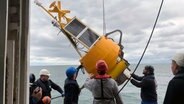 Mehrere Männer lassen eine Messboje zur Klimaforschung vom Forschungsschiff Alkor. © NDR Foto: Lornz Lorenzen