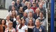 Zahlreiche Teilnehmer des interfriesischen Treffens haben sich für ein Foto auf einer Treppe aufgestellt. © NDR Foto: Karin Haug