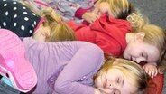 Vier Mädchen schlafen auf dem Boden. © NDR Foto: Rebekka Mehrholz