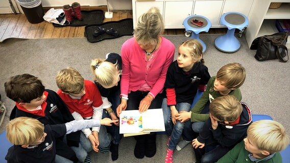 Eine Lehrerin liest ihren Schülern aus einem Buch vor. © Stiftung Louisenlund 