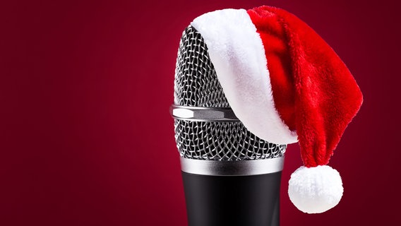 Auf einem Mikrofon liegt eine rote Weihnachtsmütze. © Fotolia Foto: Pavel Chernobrivets