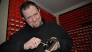 Der Ingenieur Sven Rinke hält in seiner Werkstatt ein Schloss mit Schlüssel in den Händen. © NDR Foto: Peter Bartelt