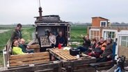 Mehrere Menschen sitzen rund um einen selbstgebauten Tisch in der Natur. © NDR Foto: Sven Jachmann