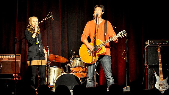 Ein junger Musiker mit Gitarre und eine junge Frau stehen auf der Bühne und singen  Foto: Maja Bahtijarevic