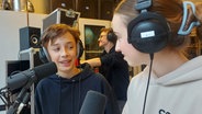 Jakob Oesterreich und Marie Heuel stehen am Mikrofon im Studio des Schulradios Bargteheide. © NDR Foto: Katharina van der Beek