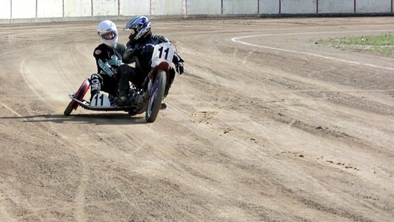 Ein Motorrad mit Beiwägen fährt auf einer sandigen Strecke. © NDR Foto: Dana Frohbös