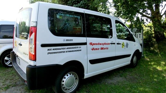 Ein Kleinbus mit Aufschriften parkt auf einer Wiese. © NDR Foto: Dana Frohbös