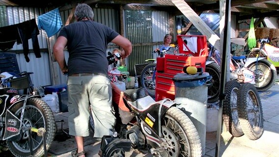 Ein Mann handtiert mit einem Motorrad. © NDR Foto: Dana Frohbös