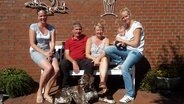 Eine fünfköpfige Familie mit Hund sitzt auf einer Bank © NDR Foto: Cassandra Arden