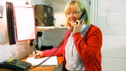 Anja Fedder steht in einer Küche und hält sich den Telefonhörer ans Ohr  Foto: Ines Barber