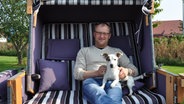 Olliver Thede in einem seiner selbst produzierten Strandkörbe, mit Jack Russel Eddie © NDR Foto: Peter Bartelt