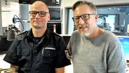 Im Studio der NDR 1 Welle Nord stehen links Christian Esselbach und Jan Malte Andresen. © NDR Foto: Anna Baake
