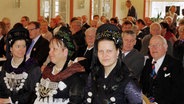 Viele Menschen in friesischer Tracht in einem Veranstaltungssaal © NDR Foto: Karin Haug