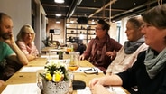 Fünf Menschen sitzen an einem Tisch und unterhalten sich  Foto: Karin Haug