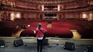 Die friesische Sängerin Norma steht auf der Bühne eines Theatersaals. © NDR 
