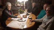 Elisabeth Ketels aus Katharinenheerd sitzt zusammen mit drei Männern am Tisch und spielt. © NDR Foto: Olliver Kring
