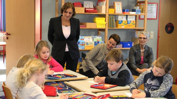 Fünf Kinder sitzen an einem Gruppentisch während des Plattdeutsch Unterrichts. Mehrere Erwachsene beobachten den Unterricht. © NDR Foto: Rebekka Merholz