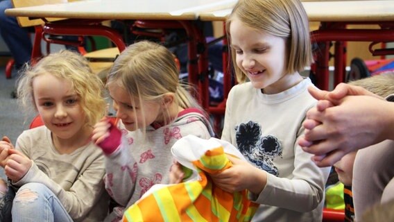 Mehrere Kinder sitzen beim Plattdeutsch Unterricht in einem Erzählkreis. Ein Mädchen hat ein Kuscheltier in der Hand. © NDR Foto: Rebekka Merholz