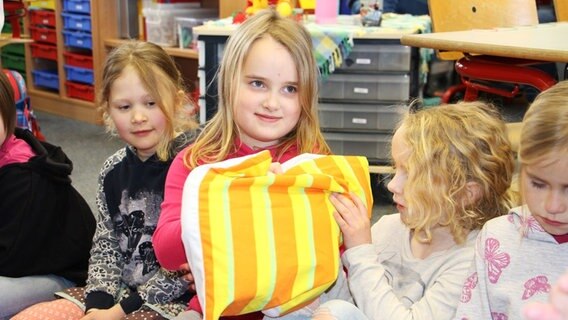 Mehrere Mädchen sitzen in einem Erzählkreis. Eines der Mädchen hält ein Kuscheltier in der Hand. © NDR Foto: Rebekka Merholz