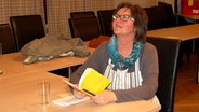 Riesebyerin Gunda Gey sitzt an einem Tisch und hält ihr Skript op Platt in Händen. © NDR Foto: Ines Barber