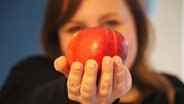 Eine Frau hält einen Apfel in der Hand.  Foto: Lina Bande