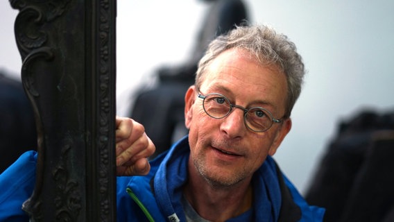 Poetry Slammer Achim Kußmann steht an einem Bilderrahmen und guckt in die Kamera. © NDR Foto: Lornz Lorenzen