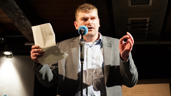 Poetry Slammer Jan Graf steht auf einer Bühne und hält einen Zettel in der Hand © NDR Foto: Petra Nowack