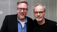 Reinhold Beckmann steht neben Jan Malte Andresen vor einer grauen Wand. © NDR Foto: Samir Chawki