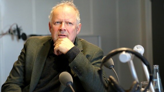 Im Interview für NDR 1 Welle Nord sitz Schauspieler Axel Milberg vor einem Mikrofon. © NDR Foto: Anna Baake