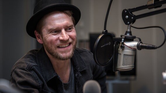 Johannes Oerding sitzt vor einem Mikrofon in einem Hörfunkstudio. © NDR Foto: Janis Röhlig