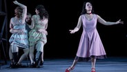 Eine Frau tanzt, während ein Mann im Hintergrund zwei Frauen im Arm hält- Eine Szene aus "Carmen" am Kieler Opernhaus. © Schauspielhaus Kiel Foto: Olaf Struck