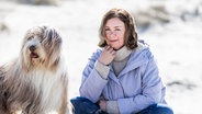 Elke Weiler sitzt mit einem Hund am Strand © Stine Jans Fotografie Foto: Stine Jans Fotografie