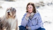 Elke Weiler sitzt mit einem Hund am Strand © Stine Jans Fotografie Foto: Stine Jans Fotografie